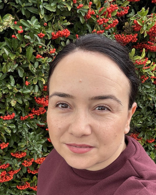 Debora Tentis in a burgundy jumper in front of an autumn hedge of red berries