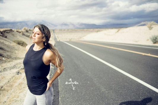 Confident athletic woman standing on a road, strong and health-focused