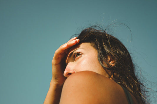 Woman shielding her eyes from strong summer sun against a clear sky