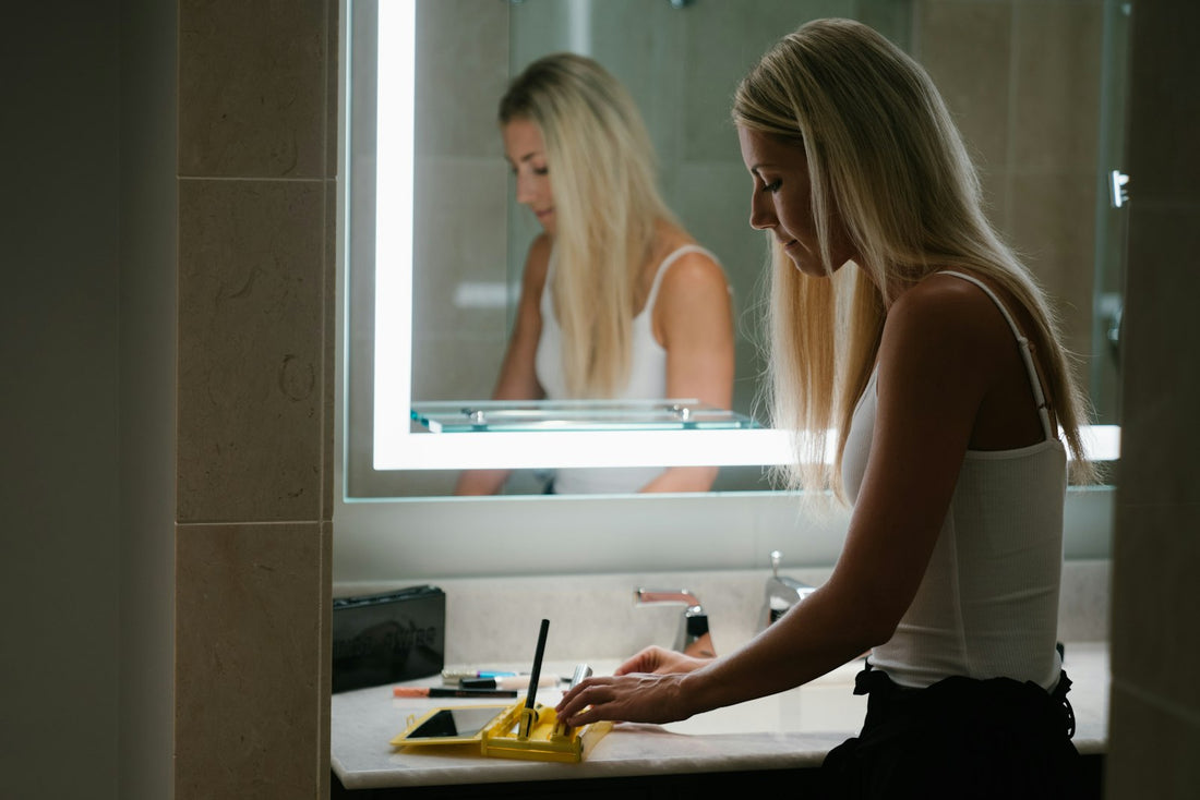 A woman standing at a bathroom mirror in the morning