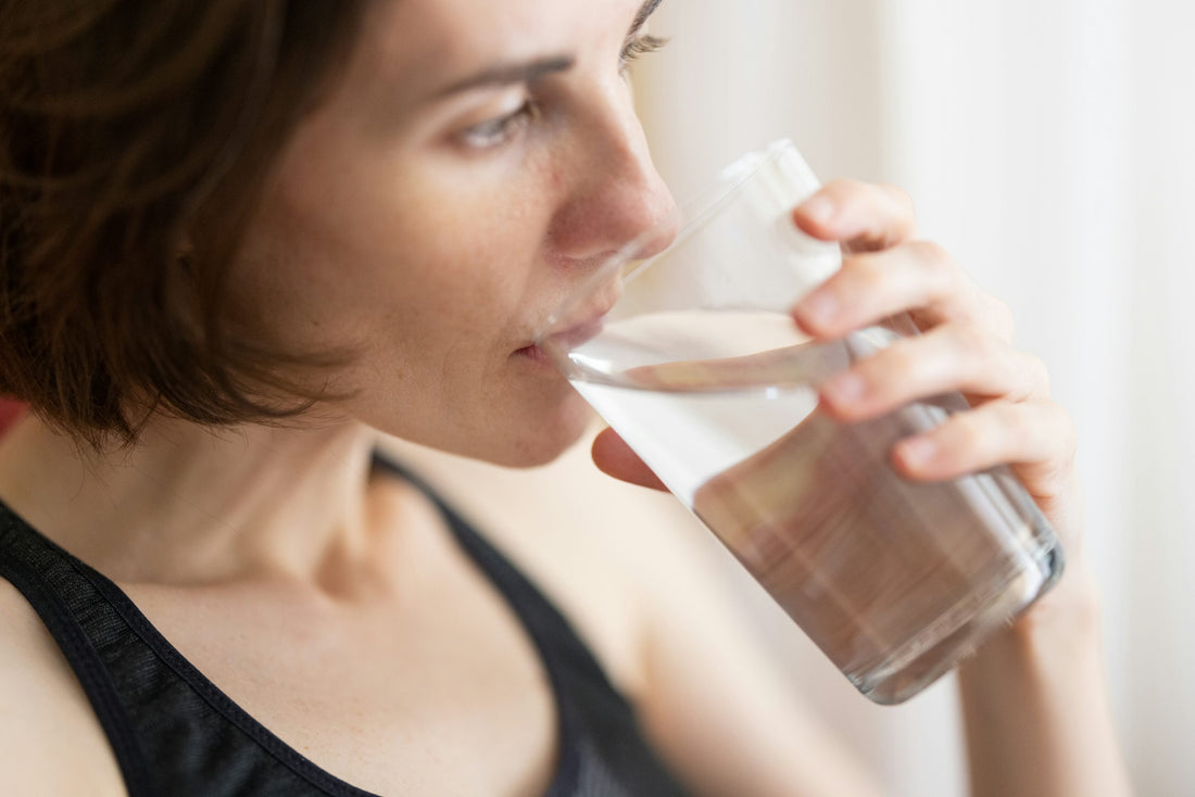 Woman in athletic top drinking a glass of water