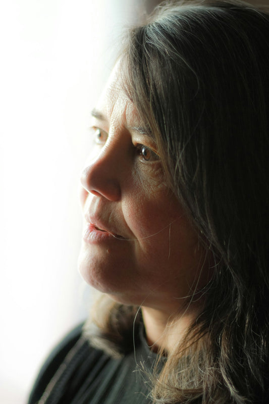 Woman looking out of a window, thoughtful, in natural light