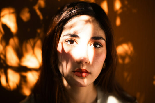 A woman's face lit by warm late summer sunlight falling through leaves