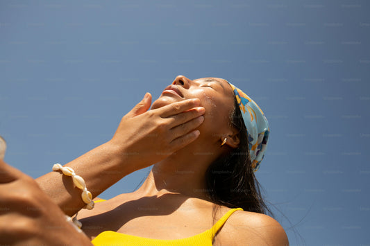 Woman applying SPF 50 sunscreen to face outdoors